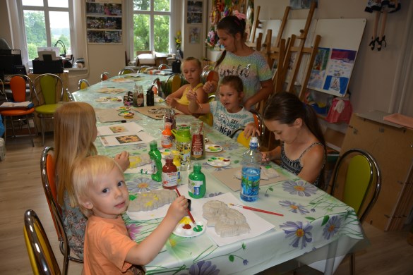 Dzieci w pracowni plastycznej malujące farbami odlewy z gipsu przedstawiające słoneczniki