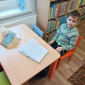 Chłopiec siedzi przy stole z książkami.